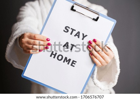 Woman holding blank with inscription stay at home calling for stop spreading covid-19.