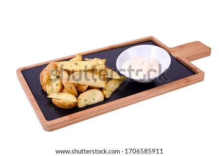 Roasted potato wedges on a wooden board with herbs and garlic sauce. isolated on a white background.