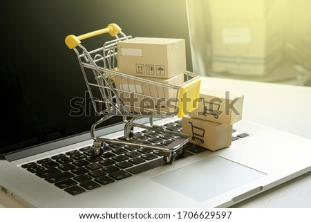 shopping cart with parcels standing on laptop. Online shopping concept