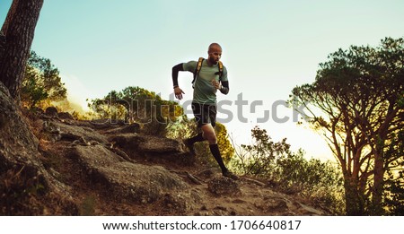 Man running on mountain trail. Fitness male running through rocky mountain path. Royalty-Free Stock Photo #1706640817
