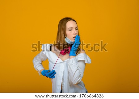 The caucasian girl in blue colored protective face mask. The girl looking at camera. Portrait shot over yellow background. virus and pollution protection concept.