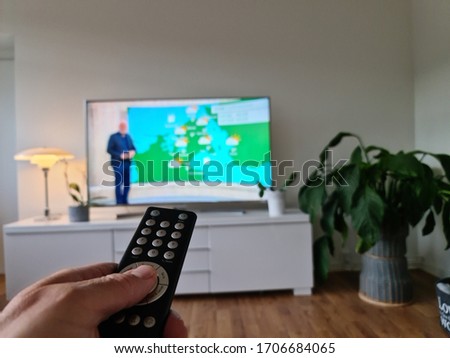 Hand holding remote control while shifting TV canals