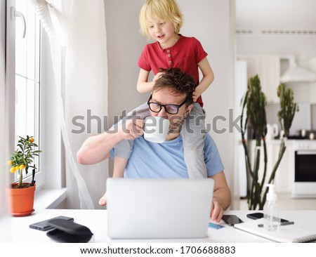 Man working from home with laptop during quarantine. Home office and parenthood at same time. Exhausted parent with hyperactive child. Chaos with kids during isolation Royalty-Free Stock Photo #1706688883