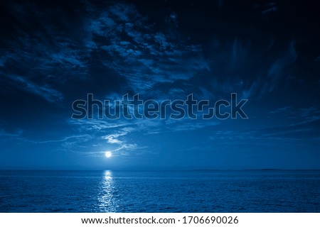 This photo illustration of a deep blue moonlit ocean and sky at night  would make a great travel background for any travel or vacation purpose. Royalty-Free Stock Photo #1706690026