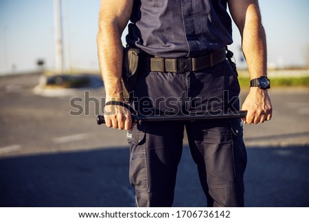 Police officer baton in hands. Policeman in action.
