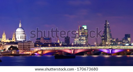 London skyline at night with bridge and St Pauls Cathedral over Thames River.