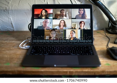 People doing a virtual meeting online.  Laptop on work from home desk.  Coworkers in a team meeting during COVID-19 coronavirus pandemic. Royalty-Free Stock Photo #1706740990