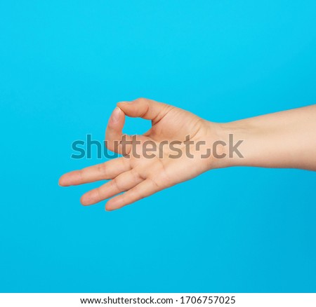 female hand shows the mudra of Knowledge on a blue background, concept of relaxation and meditation