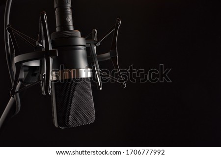 Professional Studio Condenser Microphone in Shock Mount  with Pop Filter on Left with Space for Type, Isolated on Black Background