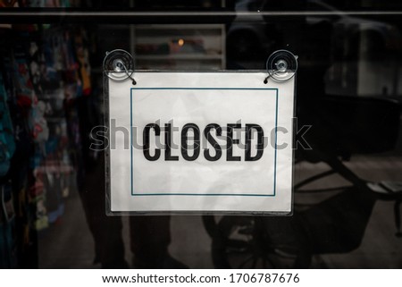 A printed paper with the words closed in bold and border hangs in a storefront or business glass window during the COVID-19 outbreak pandemic and stay at home orders effecting business and the economy