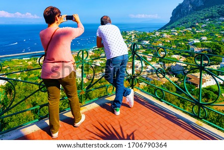 Couple of tourists at Marina Piccola in Capri Island, Italy at Naples. Landscape with people at Mediterranean Sea on Italian coast. Anacapri, Europe. View on Amalfi scenery and Solaro mountain
