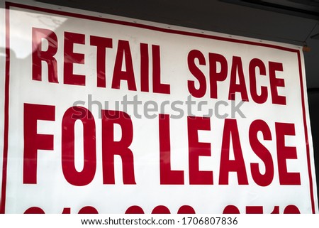 A red and white sign saying retail space for lease with border hangs in a vacant storefront glass window in Chicago during the COVID-19 or cornavirus outbreak and pandemic. Royalty-Free Stock Photo #1706807836