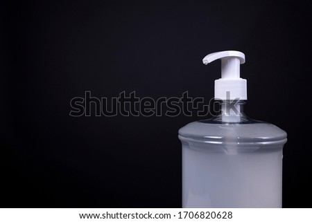 Bottle of plastic unmarked disinfecting sanitising hand gel consisting of a thick hazy non-transparent substance with white push faucet evenly lit in studio against a dark grey background Royalty-Free Stock Photo #1706820628