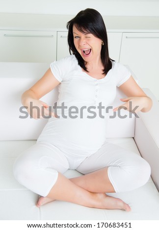 Beautiful pregnant woman smiling and pointing on the her stomach