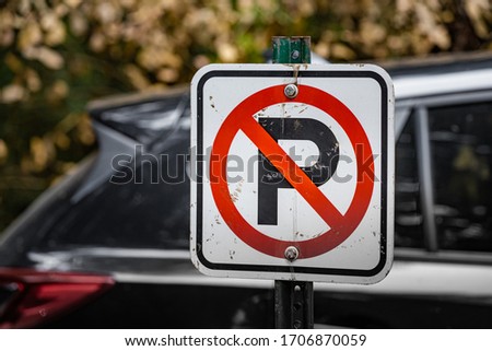 Beat Up No Parking Sign with a Car in the Backdrop