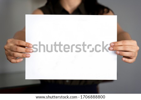 Woman holding empty rectangular sign for message. Hands holding blank paper.