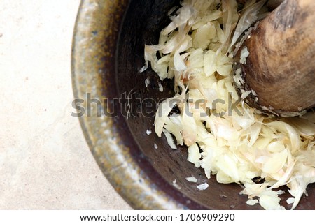 A picture of garlic that has been pounded. In a mortar with pestle.