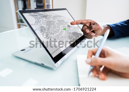 Close-up Of A Businesspeople Analyzing Cadastre Map On Computer In The Office