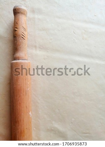 Wooden rolling pin on rolled dough.