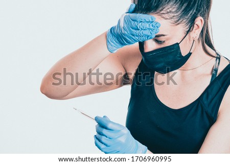 The girl in the medical mask looks at the thermometer and frowns. High temperature in a sick person. Virus epidemic concept. Close Up Royalty-Free Stock Photo #1706960995