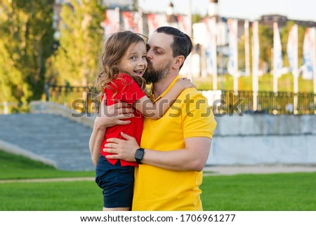Happy family on a summer walk. Dad and daughter have fun in the park. Family holiday concept. Leisure together. Family portrait. Love concept. Parent hugging embracing kissing child daughter..