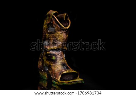 Old boot turned into a lamp (turned off in this photo) using different artistic techniques. Black background.