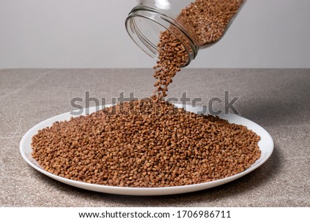 The process of pouring buckwheat from a glass jar into a plate.