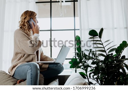 Businesswoman working on laptop computer sitting at home and managing her business via home office during Coronavirus or Covid-19 quarantine Royalty-Free Stock Photo #1706999236
