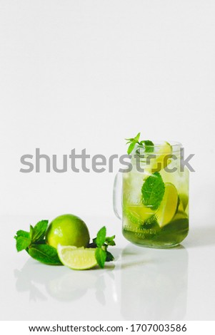 Mojito cocktail in a glass jar on a white background. Drink ingredients: cane sugar, soda, rum, lime, lemon, mint, ice. The perfect cool drink in the summer. Place for text. Top view