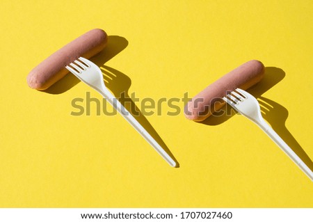 Pattern, raw sausages and plastic forks on a bright yellow background