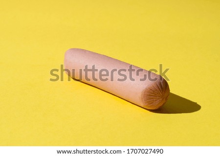 Raw sausage on a bright yellow background with hard light
