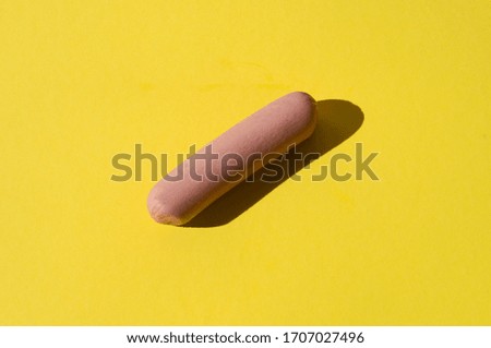 Raw sausage on a bright yellow background with hard light