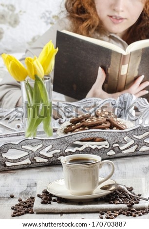 Cup of coffee. Woman reading a book in the background