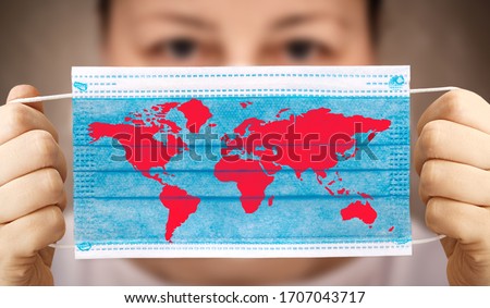 Face mask in hand with world map. Covid-19 outbreak around the world. The global economic crisis. Crash by coronavirus. Life in lockdown around the world Royalty-Free Stock Photo #1707043717