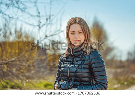 Portrait of beautiful young woman with camera in spring park