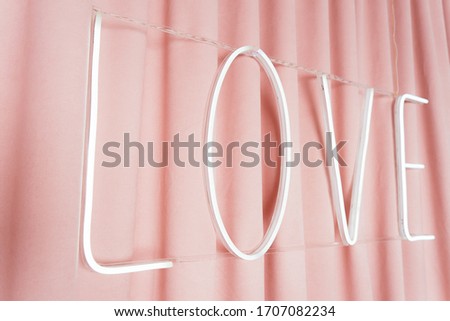 
neon inscription love on a pink curtain