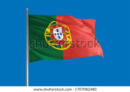 Portugal national flag waving in the wind on a deep blue sky. High quality fabric. International relations concept.