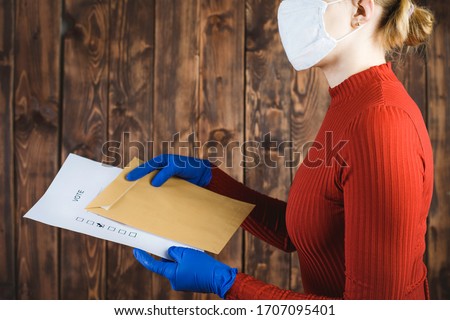 A person in blue protective gloves sends a letter with a correspondence voting card. Elections during the quarantine of the coronavirus epidemic.
 Royalty-Free Stock Photo #1707095401