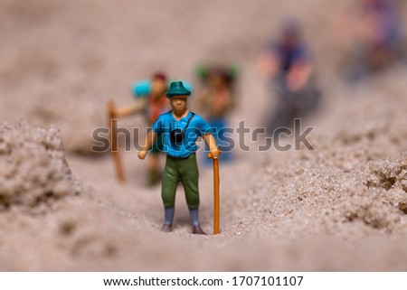 Explorer with camera and traveler's stick in the mountains. Mini world/ figure. Close up. Illustration background. Travel concept