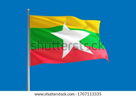 Myanmar national flag waving in the wind on a deep blue sky. High quality fabric. International relations concept.