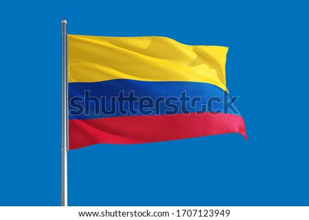 Colombia national flag waving in the wind on a deep blue sky. High quality fabric. International relations concept.