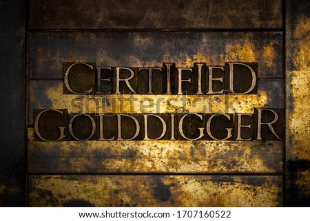 Photo of real authentic typeset letters forming Certified Golddigger text on vintage textured grunge copper and gold background