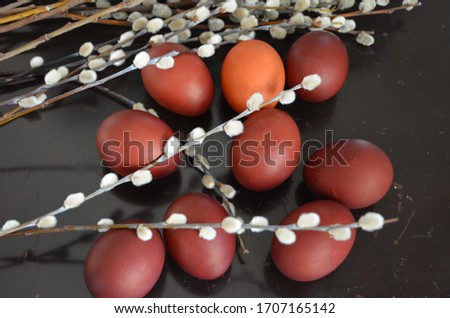 Easter 2020. Red chicken eggs painted with onion feather and willow on a black background. Russian traditional natural way of coloring eggs for Easter.
