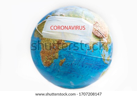 
Globe with a medical disposable mask. Globe with a mask on an isolated background with selective focus. Planet Earth with a protective mask. Prevent the concept of COVID-19
