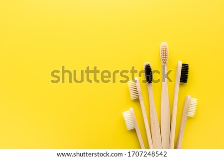 Zero waste and beyond plastic concept. Set of eco friendly bamboo toothbrushes on a bright yellow background. Flat lay, copy space, horizontal orientation. Layout natural organic hygiene products. Royalty-Free Stock Photo #1707248542