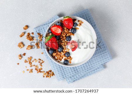 Homemade oatmeal granola smoothie bowl with berries on ligth grey background. Healthy breakfast concept. Organic oat, almond and sunflower seeds. Top view. Royalty-Free Stock Photo #1707264937