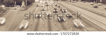 Busy frontage road and highway traffic in downtown Houston, Texas in rush hour. Long exposure slow motion cars commute on interstate highway at evening with light trail, high-occupancy vehicle lane