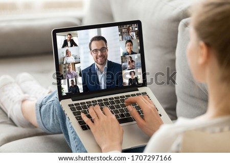 Concept of group videocall using webcam and laptop modern technologies and distant communication. View over girl shoulder resting on couch holding on lap notebook advertise worldwide virtual chat app