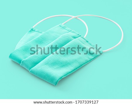 Tissue medical sterile mask of green color on a green background, close-up. Mask as a means of protection against microbes during the coronavirus and flu pandemic. Precautions in a virus epidemic.