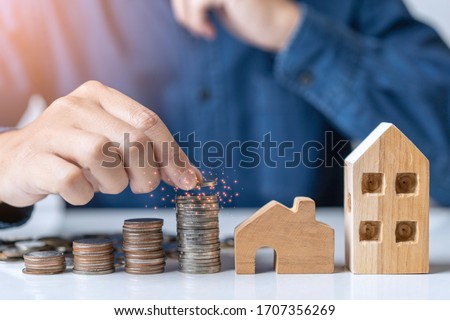 A young man thinking about bank loan, planning savings money of coins for buy a new house while Coronavirus, Covid-19 pandemic situation. Concept of Property investment and house mortgage financial. Royalty-Free Stock Photo #1707356269